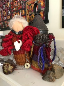 woven doll with gray hair, colorful red shawl, necklace and jewels of volcano power